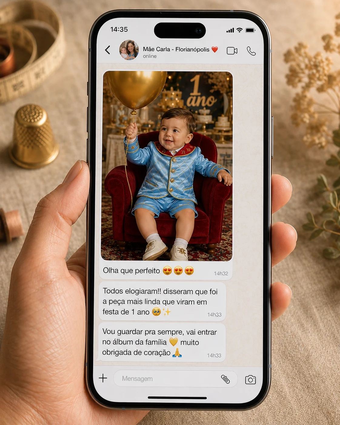 Tela de iPhone mostrando conversa de WhatsApp recebida pela costureira-aluna · contato 'Mãe Carla - Florianópolis ❤️' · 3 mensagens com foto do bebê em festa de 1 ano vestindo Conjunto Príncipe Luxo + bexiga dourada na mão + textos 'Olha que perfeito 😍😍😍' / 'Todos elogiaram!! foi a peça mais linda que viram em festa de 1 ano 🥹✨' / 'Vou guardar pra sempre, vai entrar no álbum da família 💛 muito obrigada de coração 🙏'